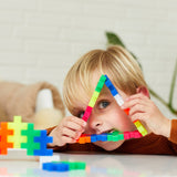 Young boy looking through a triangle shape made of colorful Plus-Plus BIG building blocks.