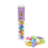 Clear tube of Plus-Plus BIG blocks in pastel colors, including pink, blue, green, yellow, and white. Some pieces are scattered outside.