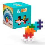 A colorful toy block set on a white background. The box features a rainbow and says "Plus Plus BIG". Blocks form a vibrant, tiered structure.