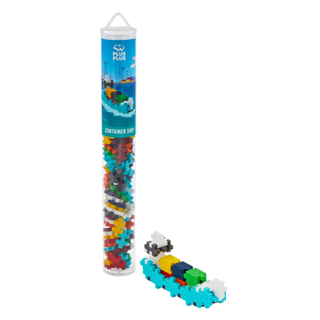 A Plus-Plus container ship toy set in a tall, clear tube showing colorful interlocking pieces. Assembled mini ship beside it. White background.