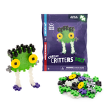 Toy packaging for "Plus-Plus Creepy Critters Bolt" featuring colorful interlocking pieces. A completed monster with green face, big yellow eyes, and white legs is assembled beside a pile of loose pieces. Glow-in-the-dark feature highlighted.