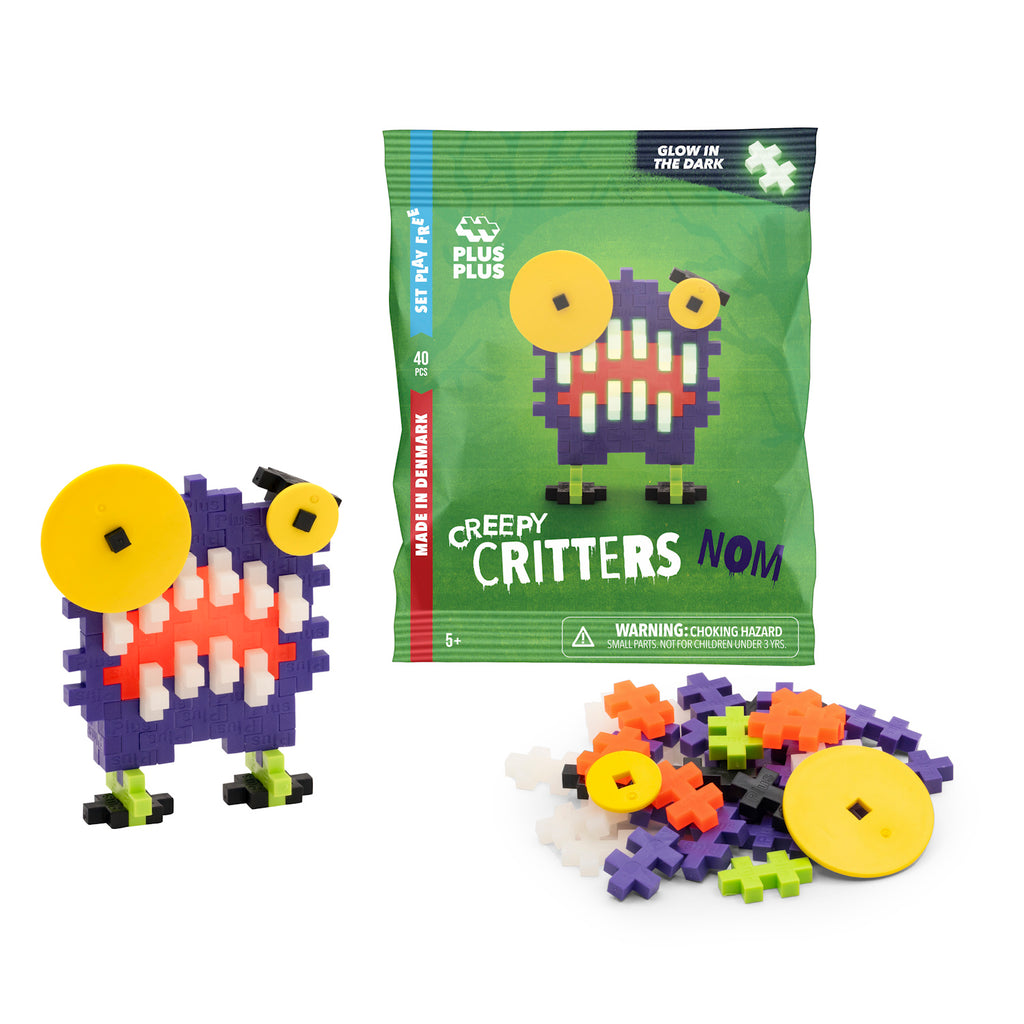 Toy construction set featuring colorful interlocking pieces and a completed toy monster with a large yellow eye, set beside green packaging.