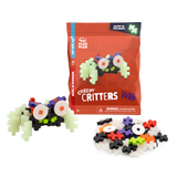 Package of Plus-Plus "Creepy Critters" featuring glow-in-the-dark pieces, shown with a partially assembled creature in colorful plastic blocks.