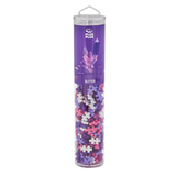 Tall, clear tube with colorful interlocking plastic pieces in purple, pink, and white. The purple label reads "Plus-Plus Glitter" and features crystal graphics.