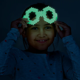 A smiling child in a star-patterned sweater holds glowing, pixelated glasses against a dark background, radiating playful joy and whimsy.