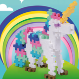 Plus-Plus unicorn building toy with colorful mane and tail standing in front of a bright rainbow illustration.