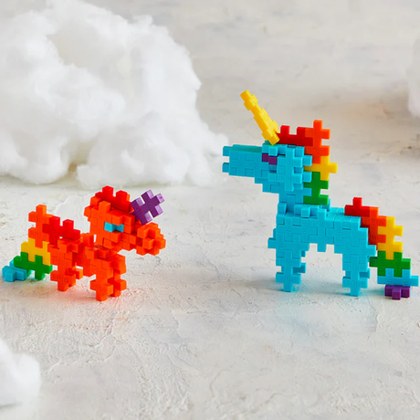 Toy unicorns built from colorful interlocking blocks: one blue with a yellow horn, the other orange with a purple horn, set against a cloud-like backdrop.