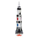 A pixelated rocket made of interlocking blocks features black dots and colorful patterns of red, blue, and gray, against a solid white background.