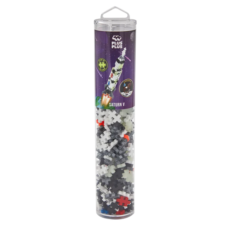 A clear cylindrical container holds Plus-Plus building pieces. The label depicts a rocket titled "Saturn V" against a starry background, suggesting space-themed play.