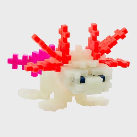 Plus-Plus axolotl building set figure with glow-in-the-dark white body, pink gills, and a purple tail on a gray background.