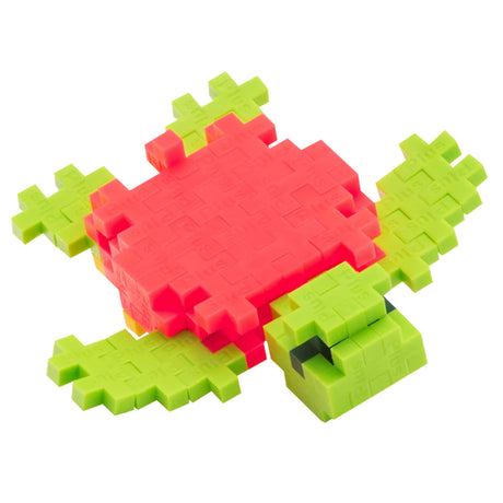 Plus-Plus building blocks sea turtle toy construction with green flippers and a pink shell on a white background.