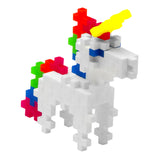 White unicorn figurine made of Plus-Plus interlocking building blocks with a yellow horn and multicolored mane and tail.