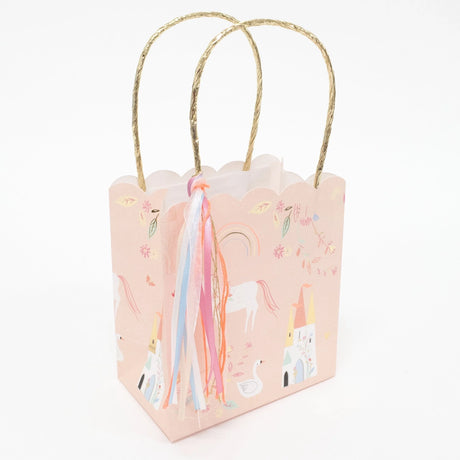 Pink unicorn-themed gift bag with gold handles and colorful ribbons.
