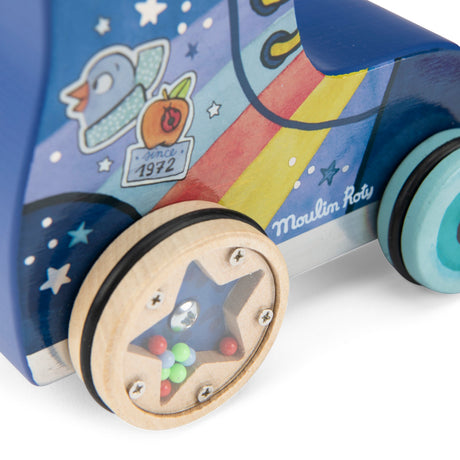 Wooden pull-along roller skate toy with a rainbow design, star-shaped rattle wheels, and "Moulin Roty" branding.
