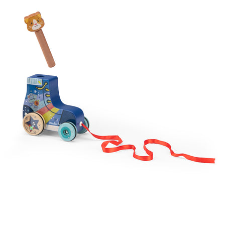 Wooden pull-along roller skate toy with a red ribbon and a separate cat-head peg against a white background.