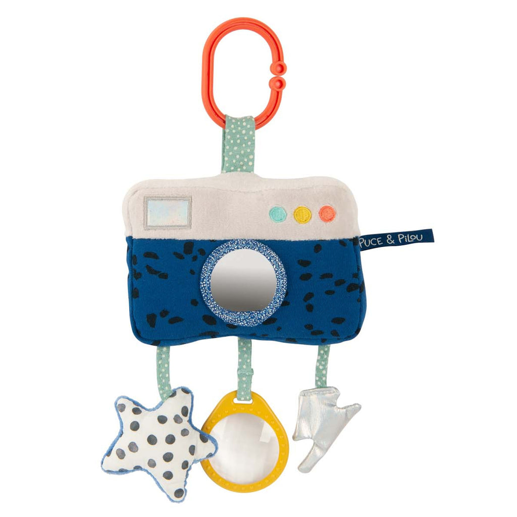 Plush camera-shaped baby toy with polka dots features a red ring clip, a mirror lens, and dangling star, circle, and arrow shapes in soft colors.