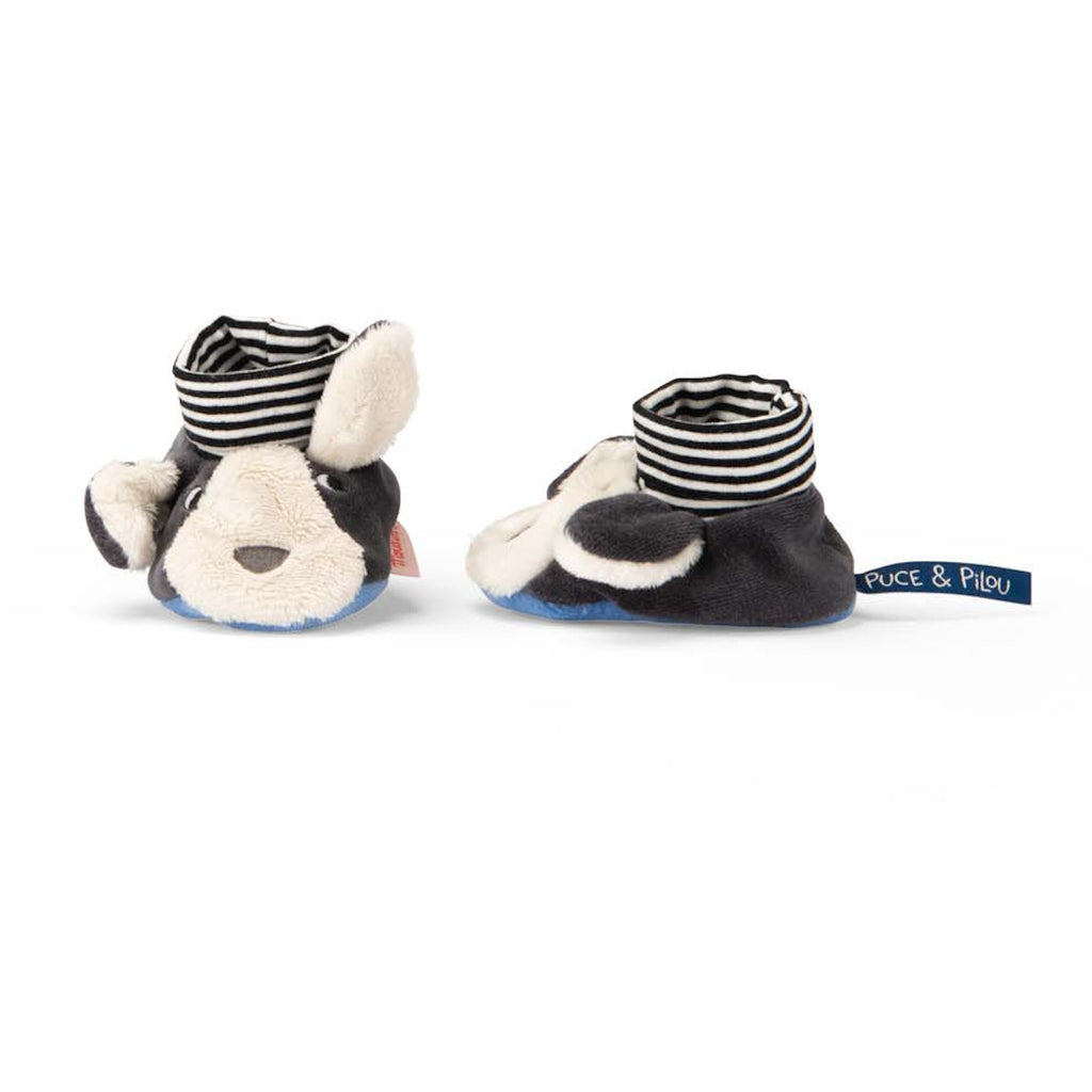 Cute baby slippers designed as playful black and white dogs with floppy ears and striped socks. The cozy, whimsical design evokes warmth and joy.