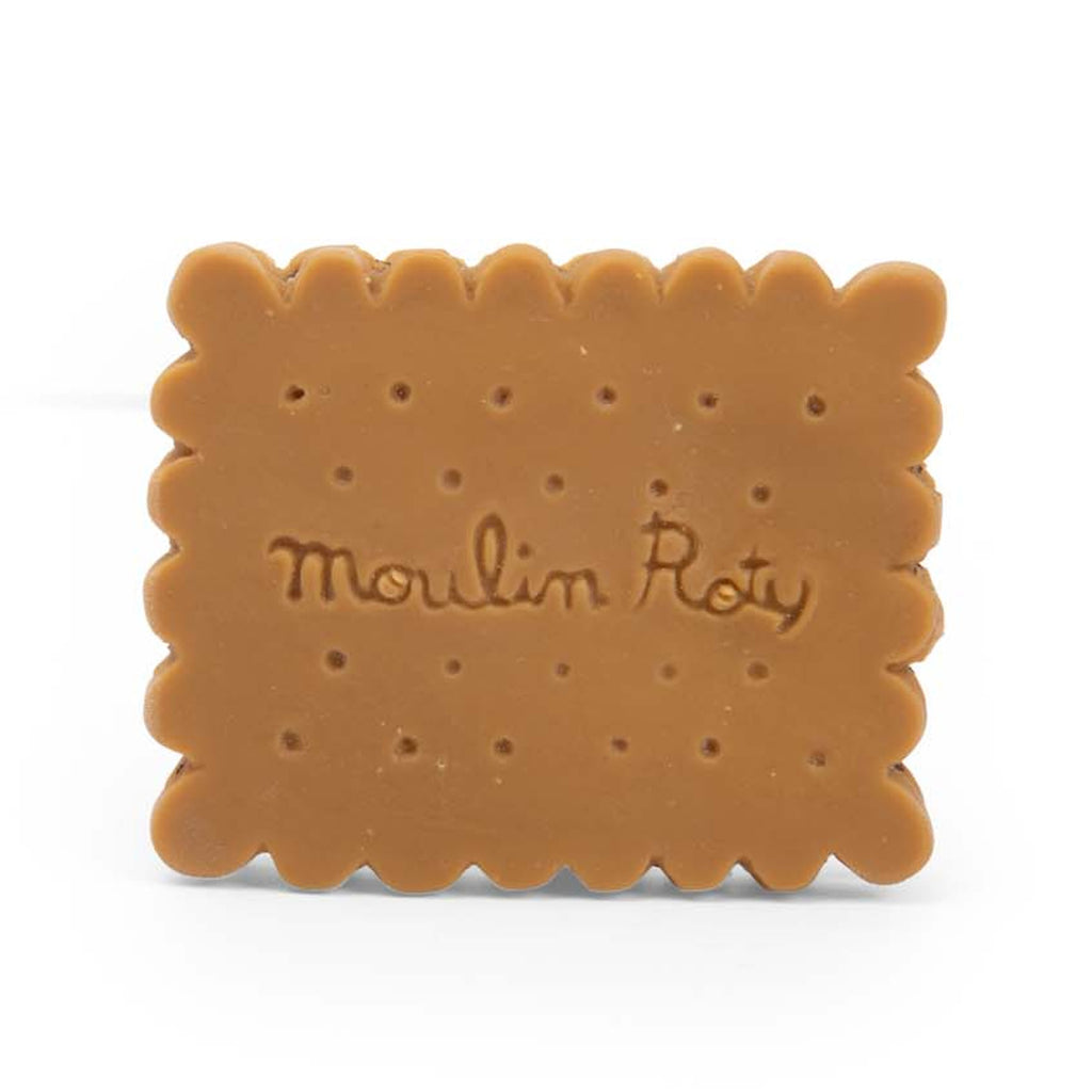 A rectangular, toy cookie made of rubber, mimicking a sandwich biscuit with scalloped edges and embossed with "Moulin Roty" on a white background.