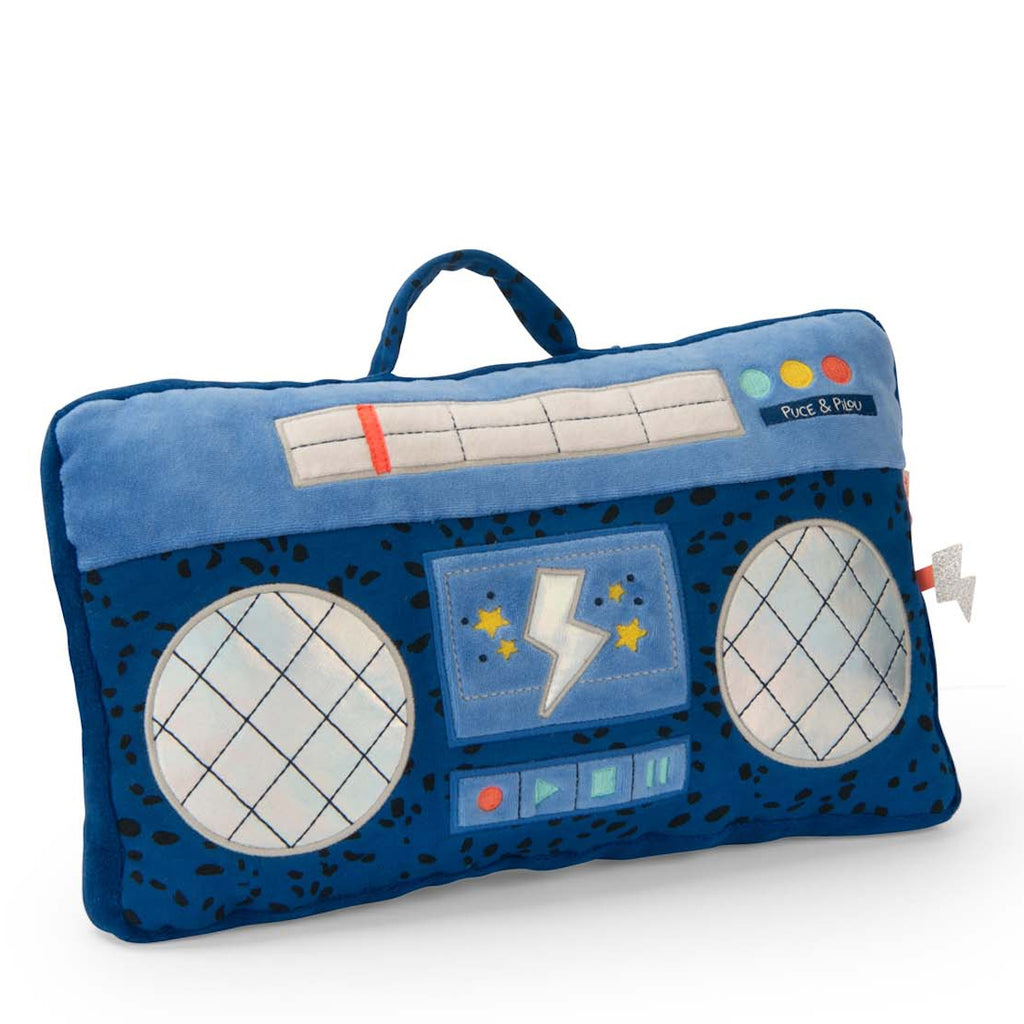 Plush rectangular cushion shaped like a blue boombox, with circular speakers, colorful buttons, and a handle. It has playful, retro design elements.