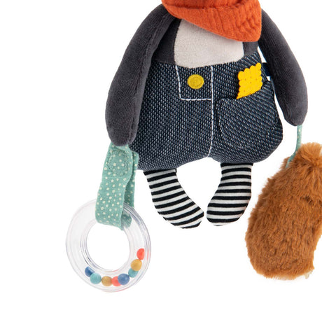 Plush activity dog toy wearing denim overalls and holding a clear rattle with colorful beads.