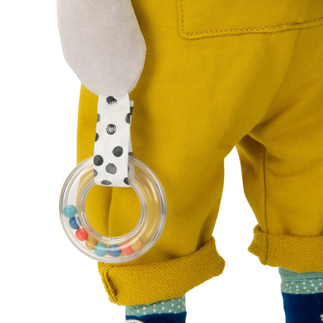 Close up of a clear plastic ring rattle accessory on a plush dog activity toy in yellow overalls.