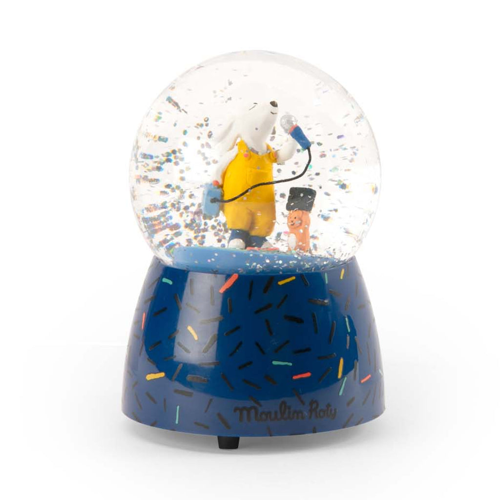 A whimsical snow globe featuring a white dog in yellow overalls singing with a blue microphone. It stands on a blue base with colorful sprinkles.