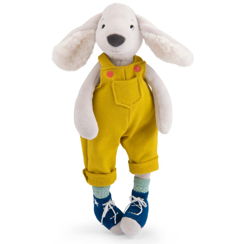 Plush toy of a dog in yellow overalls with pink buttons, polka dot socks, and blue shoes. It has floppy ears and a friendly expression.