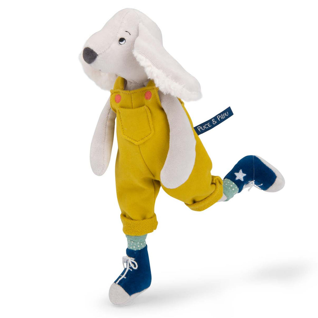 Plush toy of a dog in yellow overalls with pink buttons, polka dot socks, and blue shoes. It has floppy ears and a friendly expression.