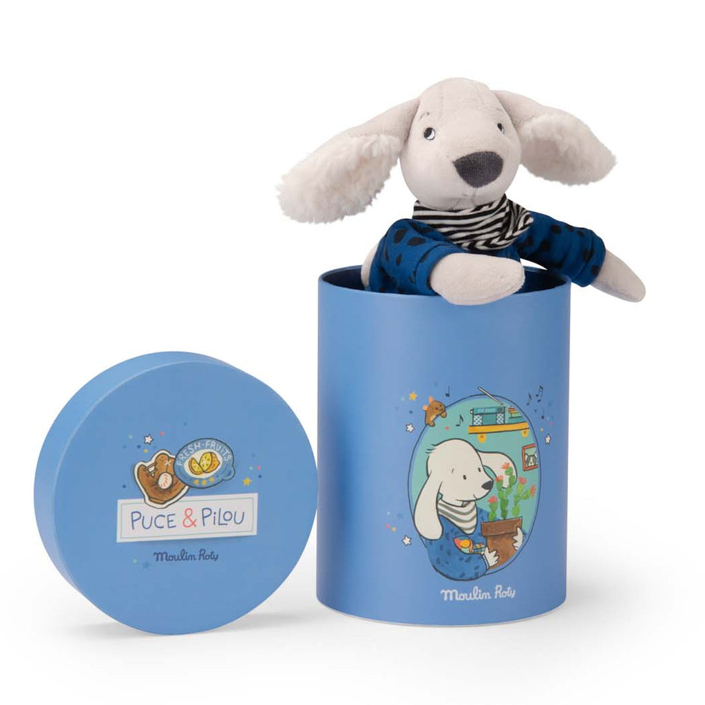 Cute plush dog with floppy ears wearing a striped shirt and blue pants, sitting in a blue cylindrical box with playful illustrations and text.