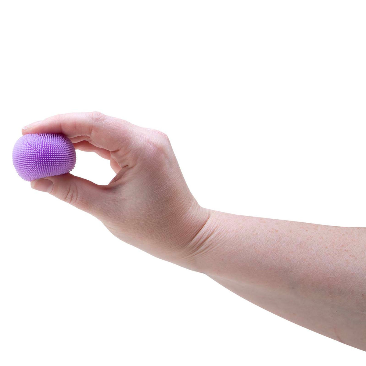 A person holding a small, purple, spiky sensory ball between their fingers against a white background.