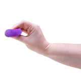 A hand pinching and squishing a small, textured purple fidget ball against a white background.
