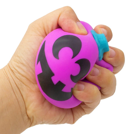 Hand squeezing a purple Schylling NeeDoh Jack-Glow lantern stress ball with a black jack-o'-lantern face and blue stem.