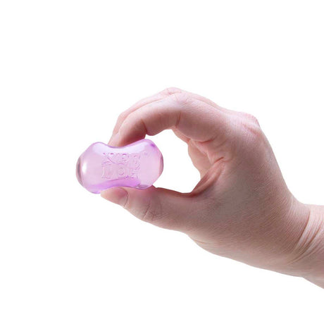A hand squeezing a small, squishy purple ice cube fidget toy against a white background.