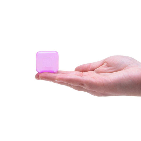 A person's open hand holding a small, translucent purple cube toy on the fingertips.