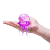 Purple glittery NeeDoh Jelly Squish jellyfish fidget toy held in a person's palm, showing its size and tentacles.