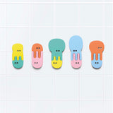 Five colorful, interlocking foam jellyfish bath toys stuck in a row on a white tiled wall.