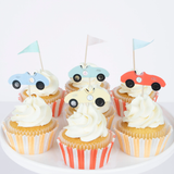 Group of cupcakes with striped liners, swirled frosting, and vintage race car and flag toppers.