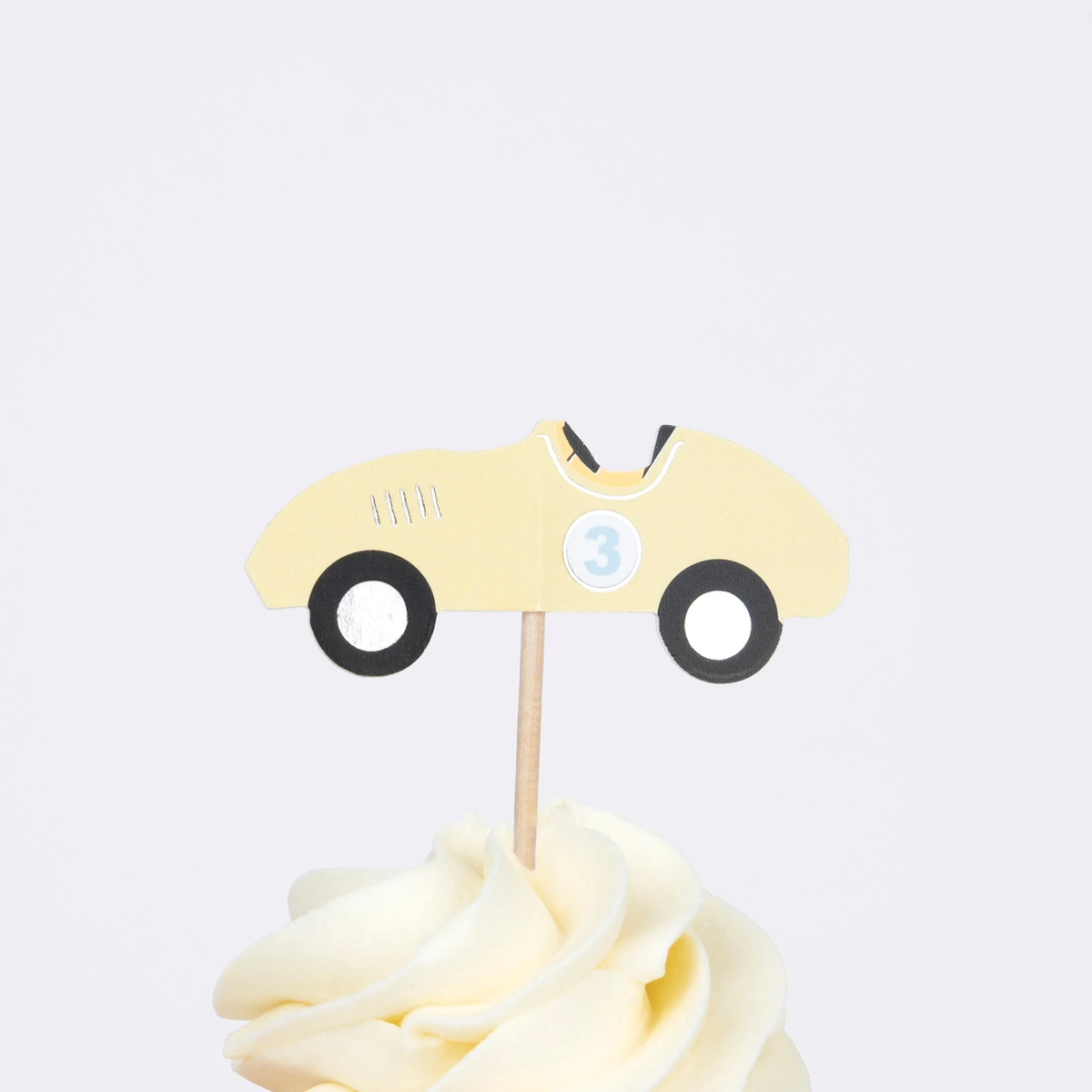 Yellow vintage race car cupcake topper with number three on a wooden pick in swirled frosting.