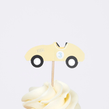 Yellow vintage race car cupcake topper with number three on a wooden pick in swirled frosting.