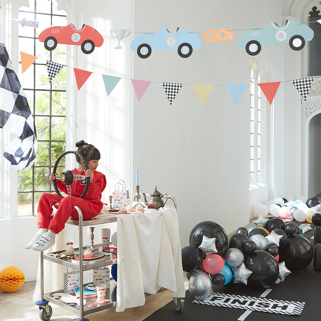 Featuring colourful paper race cars strung together with checkered flags, perfect for decorating kids' parties or car-themed events.