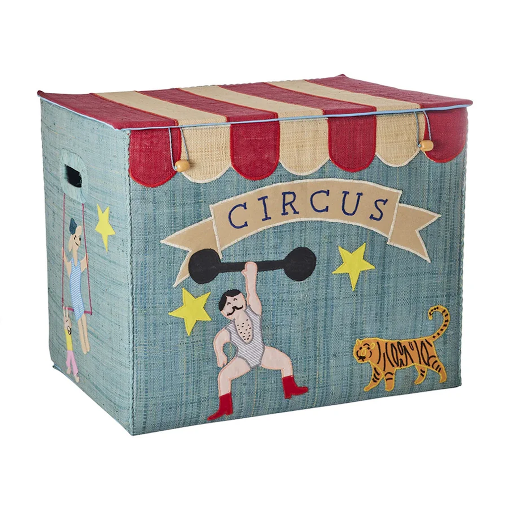 Circus-themed storage box with a red and beige striped lid. Features a strongman, trapeze artist, stars, tiger, and the word "CIRCUS" on a banner. Playful tone.
