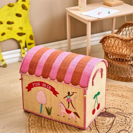 Raffia toy basket shaped like a circus tent with "Fun Fair" embroidered on it, sitting in a playroom.