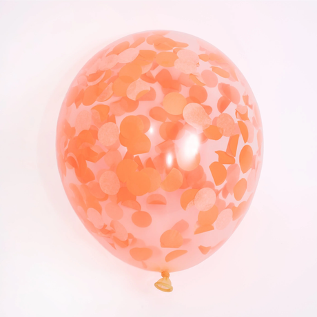 Single inflated clear party balloon filled with orange round tissue paper confetti against a white background.