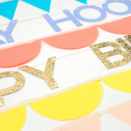 Close-up of birthday garland strands showing gold glitter lettering, purple text, and scalloped paper banners.