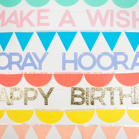 Close-up of pastel garland strands featuring pink "Make a Wish", purple "Hooray", and gold glitter letters.