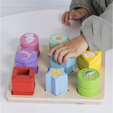 Child playing with a colorful wooden shape sorter puzzle board featuring animal and plant designs.