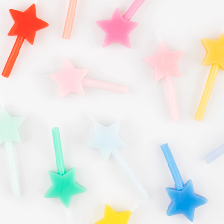 Top view detail of colorful star-shaped birthday candles loosely spread out on a white surface.