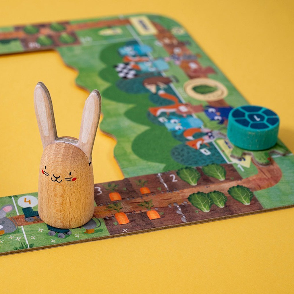 Wooden bunny token on a colorful board game surrounded by farming illustrations, including carrots and green leaves, set against a yellow background.
