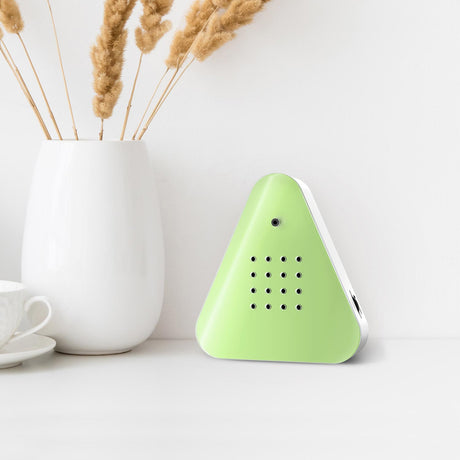 A triangular green device with a smooth surface, featuring a small camera and multiple circular holes on the front. It conveys a modern, minimalist design.