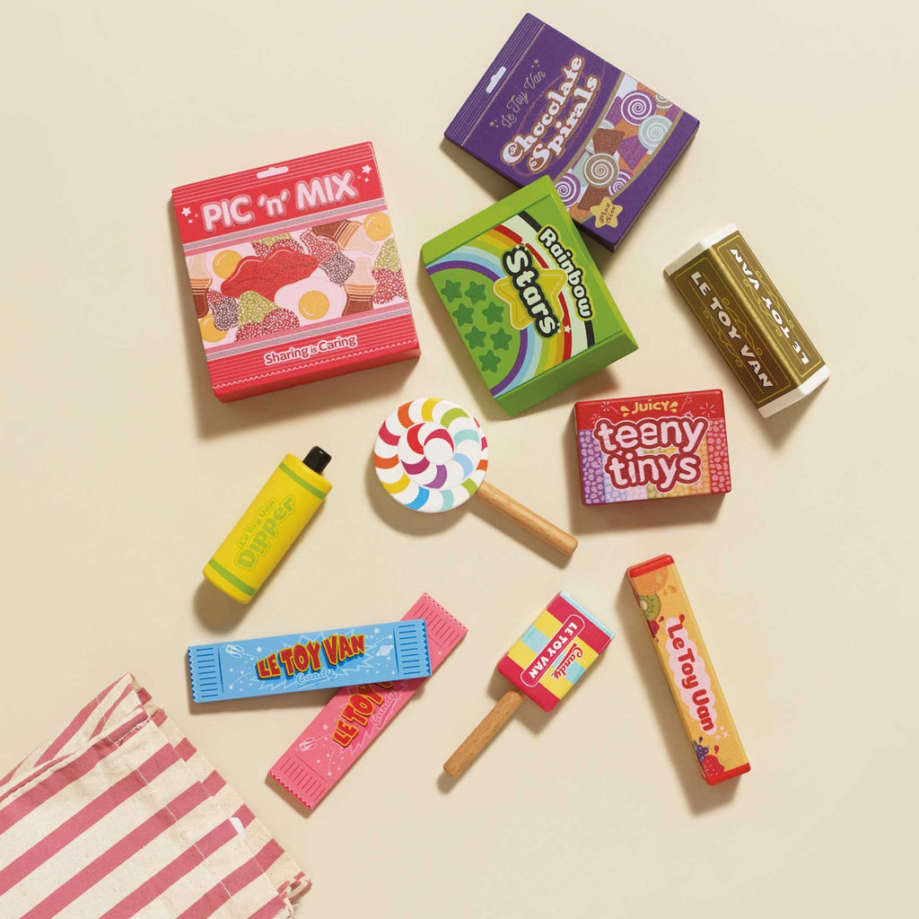 A vibrant assortment of colorful toy candies with labels like "Le Toy Van" and "Rainbow Stars". Playful and cheerful atmosphere.